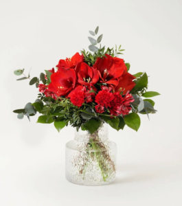 Decemberbuketten, en stämningsfull julbukett i rött, med amaryllis, nejlikor, alstroemeria och grönt. Beställ blommorna i Interflora s e-butik - skicka dem med blommogram!