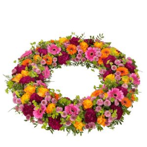 Begravningskrans med rosor, germini, santini och grönt. Blommorna i blandade, glada färger. Skicka kransen med ett blomsterbud direkt till aktuell begravning - beställ blommogrammet enkelt och snabbt på nätet.