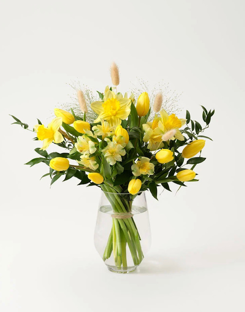 Pigg påskbukett, med gula påskliljor, gula tulpaner, gul alstroemeria, lagurus och gröna blad. Beställ blommorna hos Interflora - skicka dem med bud!