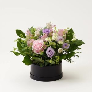 Söt blomsterdekoration i rund ask, med blandade blommor i ljusa sommarfärger. Beställ hos Interflora!
